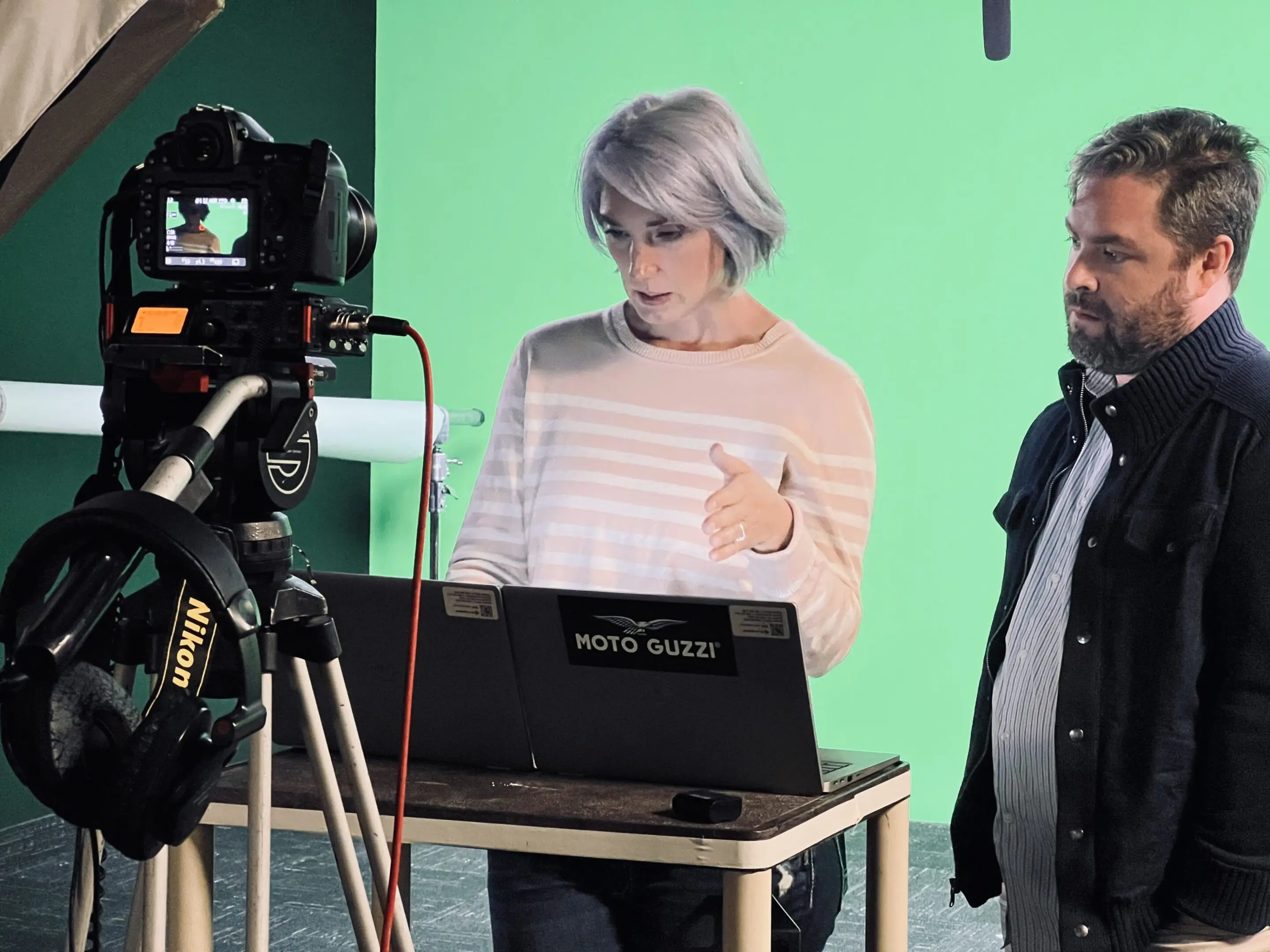 Two men working on video production with camera and laptop.