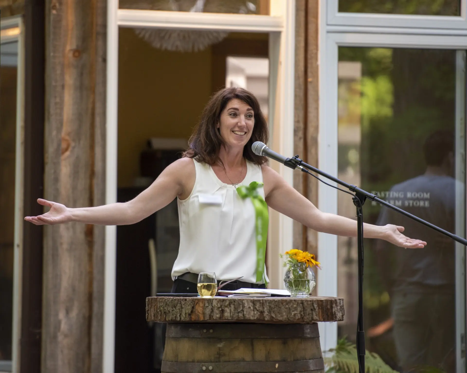 Woman speaking joyfully at an outdoor event with open arms.